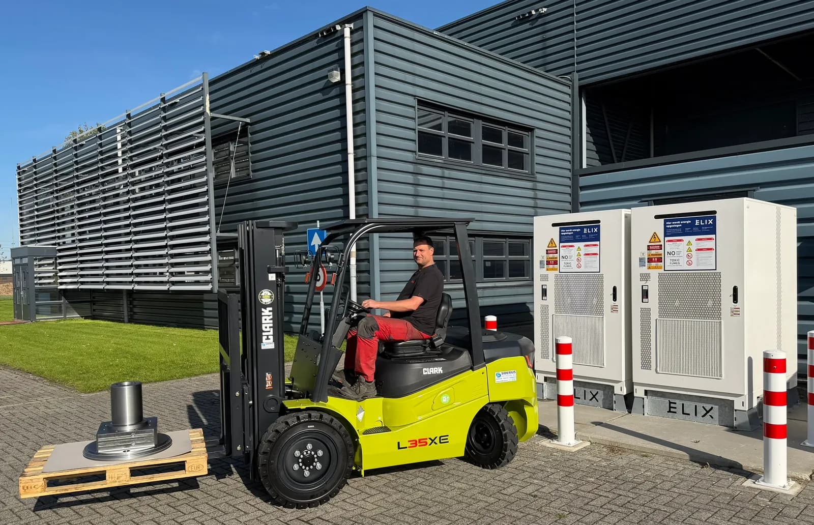 Elektrische Clark L35XE met bestuurder naast de batterijopslag bij het Douna-pand aan de Hidalgoweg.