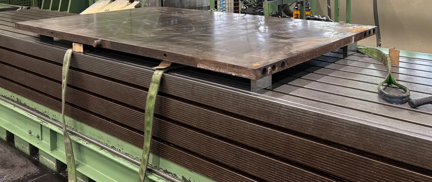 Persplaat ondersteund op de machinetafel, met verwarmingskanalen zichtbaar in de zijkant